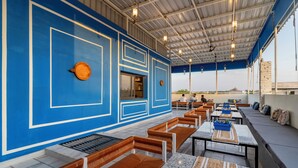 Un restaurant aux murs bleus, avec des bancs en bois et des tables dotées de coussins bleus.