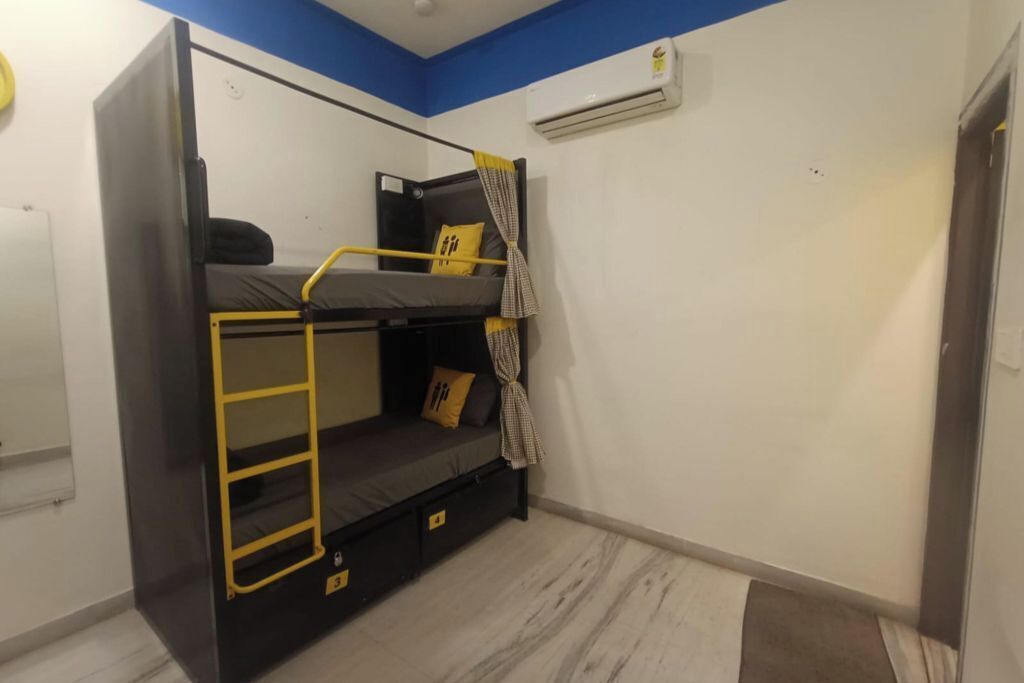 Habitación con literas, una pequeña mesa de estudio y un aire acondicionado.