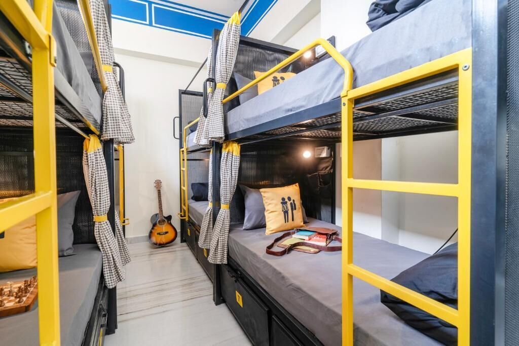 A dormitory room with bunk beds, a guitar, and a small table with books.