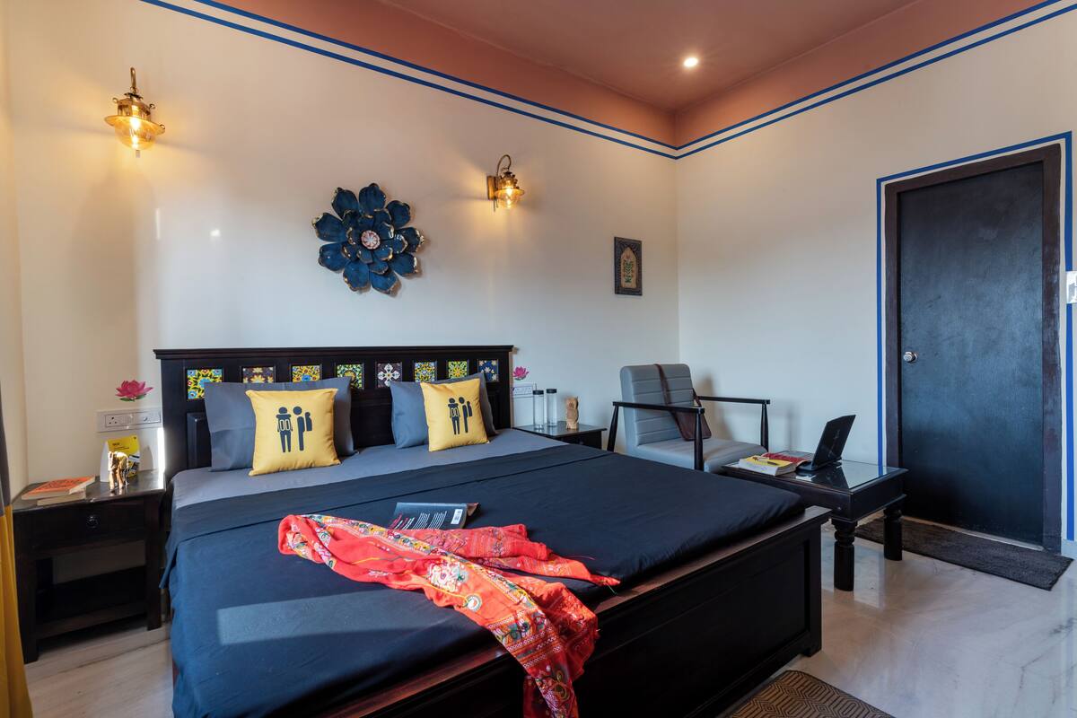 Une chambre bien rangée, avec un grand lit, des tables de chevet, un bureau et une porte.