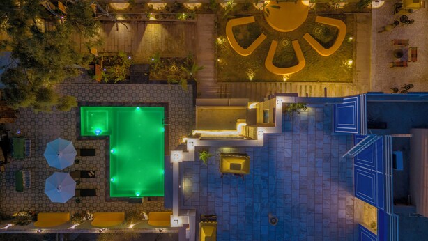 Vue aérienne d’un hôtel doté d’une piscine, d’un espace extérieur aménagé et d’un grand logo illuminé.