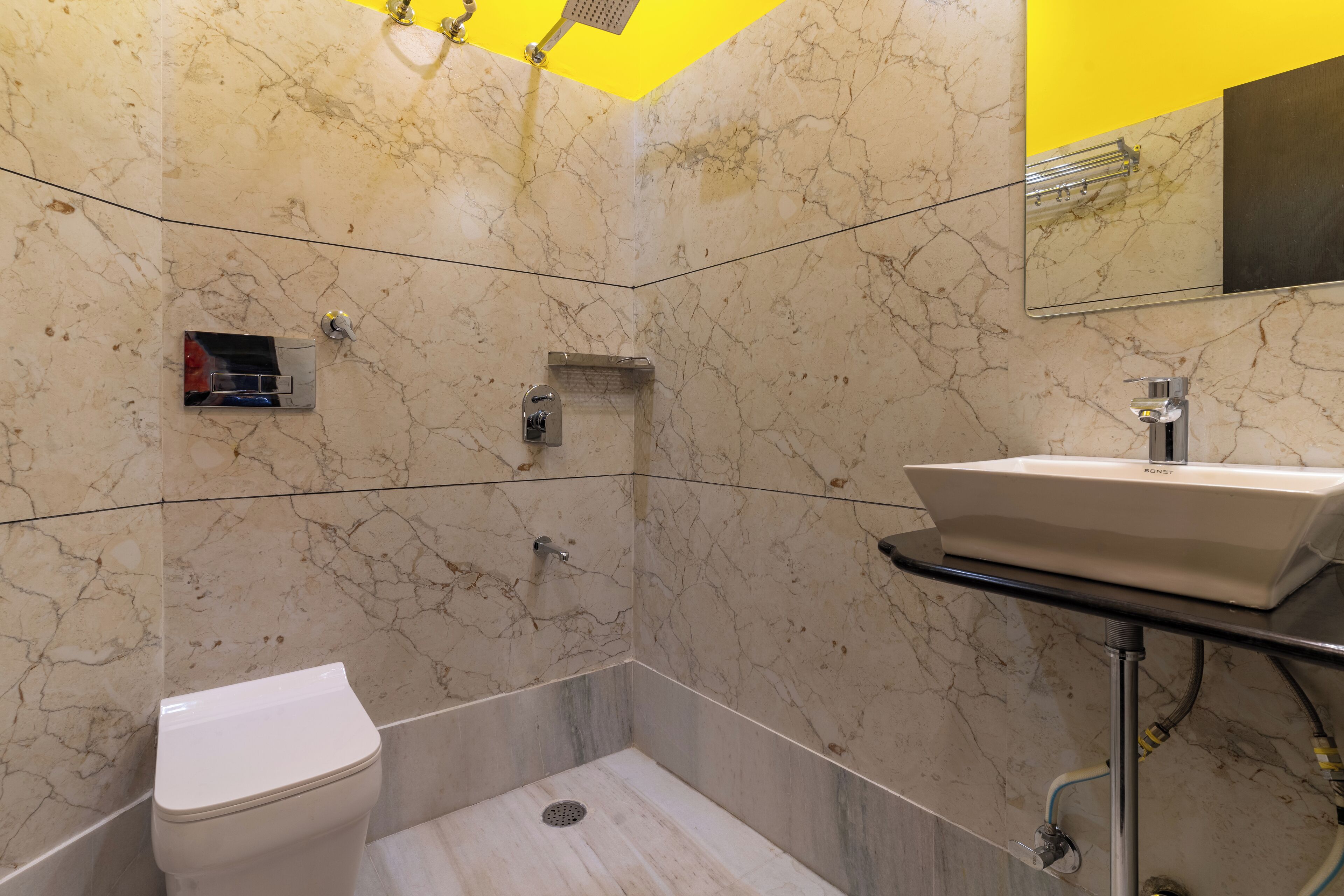A bathroom with a toilet, a sink, and a shower area with a yellow ceiling.