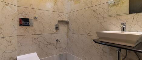A bathroom with a toilet, a sink, and a shower area with a yellow ceiling.