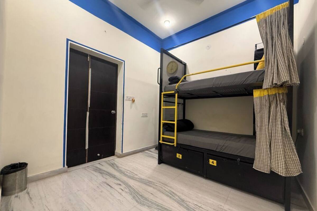 Une pièce avec un lit superposé, une porte et une petite poubelle.