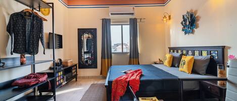 A bedroom with a bed, bedside tables, a wardrobe, a mirror, and a window with curtains.