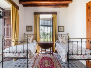 Una camera con due letti, un tavolo di legno e una finestra con tende.