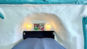 A bed in a room with a white wall and a painting above it. - Cave House in Cúllar near Tabernas Desert (Cúllar)