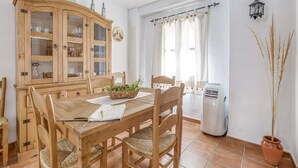A dining area with a wooden table and chairs, a cabinet with glass doors, and a potted plant. - Villa in Carcabuey near Sierras Subbeticas Park (Carcabuey)