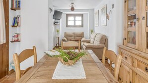 A cozy living room with a wooden dining table, two sofas, a TV, and a cabinet. - Villa in Carcabuey near Sierras Subbeticas Park (Carcabuey)