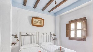 A bedroom with two beds, a wooden ceiling, a window with shutters, and a framed picture on the wall. - Villa in Carcabuey near Sierras Subbeticas Park (Carcabuey)