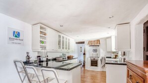 Een moderne keuken met witte kastjes, een centraal eiland en een inbouwoven.