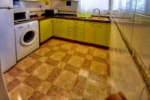Cocina con lavadora, lavaplatos y armarios amarillos.