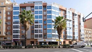 A multi-story building with a mix of commercial and residential units. - Apartment near Beach with Serene Garden (Valencia)