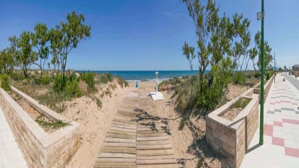 A wooden pathway leading to a beach with a clear view of the sea. - Apartment near Beach with Serene Garden (Valencia)