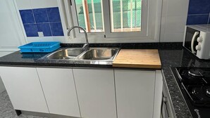 A kitchen with white cabinets, a black countertop, a sink, a toaster, and a window with a view of greenery. - Apartment near Beach with Serene Garden (Valencia)