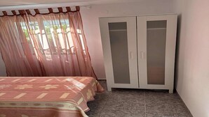 A bedroom with a bed, a wardrobe, and a window with sheer curtains. - Apartment near Beach with Serene Garden (Valencia)
