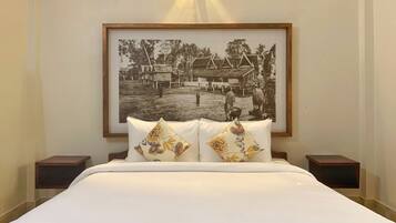 A bed with white bedding and two decorative pillows, a framed black and white photograph above the bed, and two bedside tables with lamps.