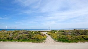 A sandy beach path leading to a white sign, with a clear blue sky and ocean in the background. - Penthouse in Denia with Private Terrace (Denia)