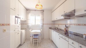 A kitchen with white cabinets, a granite countertop, a dining table with chairs, and a decorative stained glass light fixture. - Penthouse in Denia with Private Terrace (Denia)