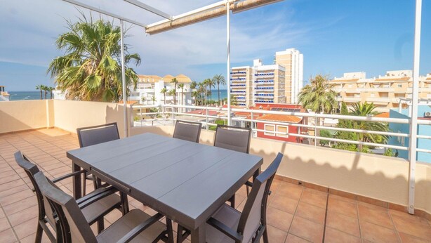 A terrace with a table and chairs, overlooking a coastal cityscape with palm trees and buildings. - Penthouse in Denia with Private Terrace (Denia)