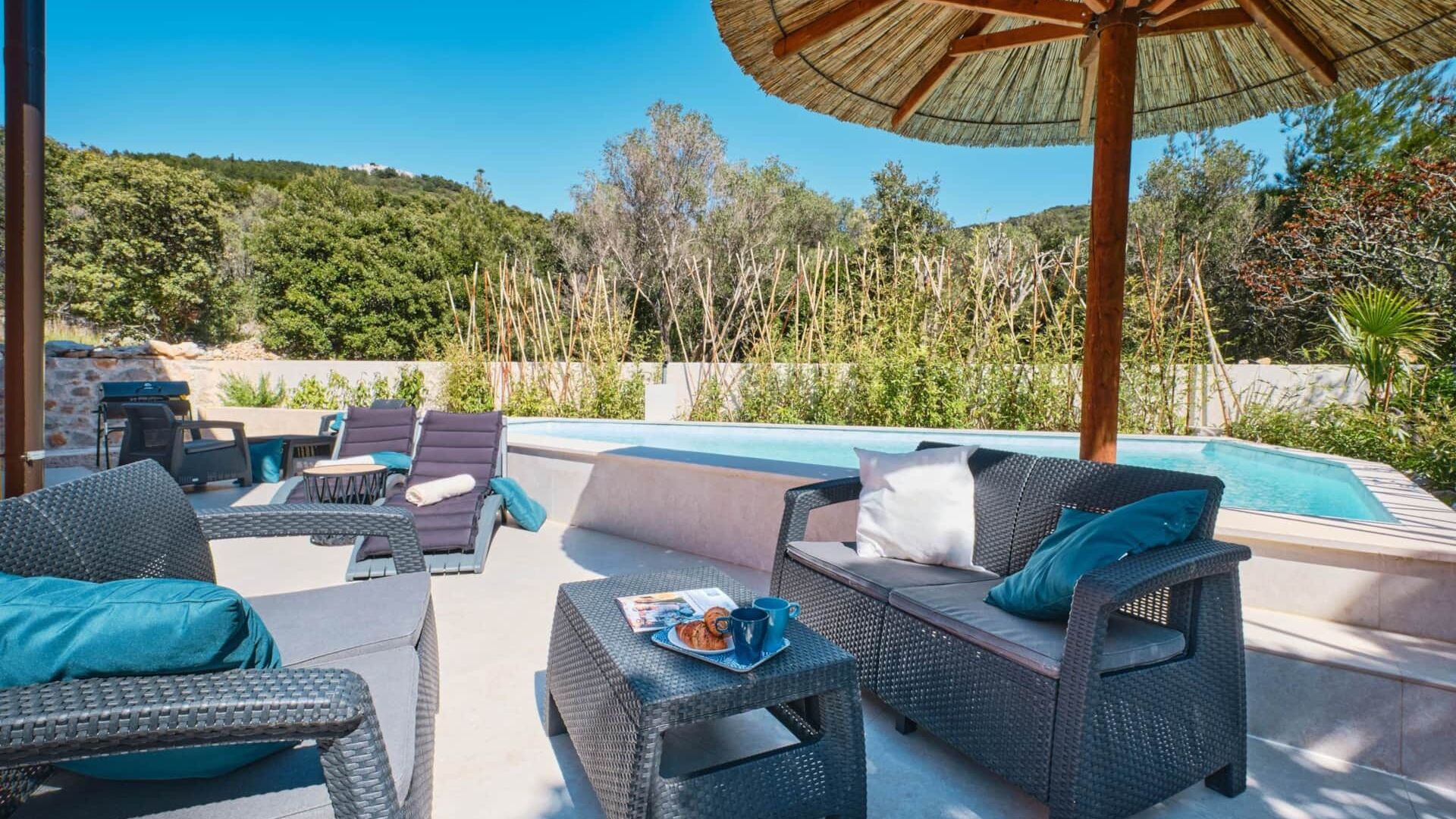 A poolside area with wicker furniture, a grill, and a pool.
