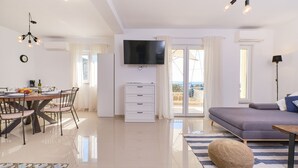 Una sala de estar moderna con comedor, televisor de pantalla plana y balcón con vistas.