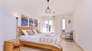 Un dormitorio con una cama de madera, una mesita de noche, una silla y vistas al exterior a través de una puerta.
