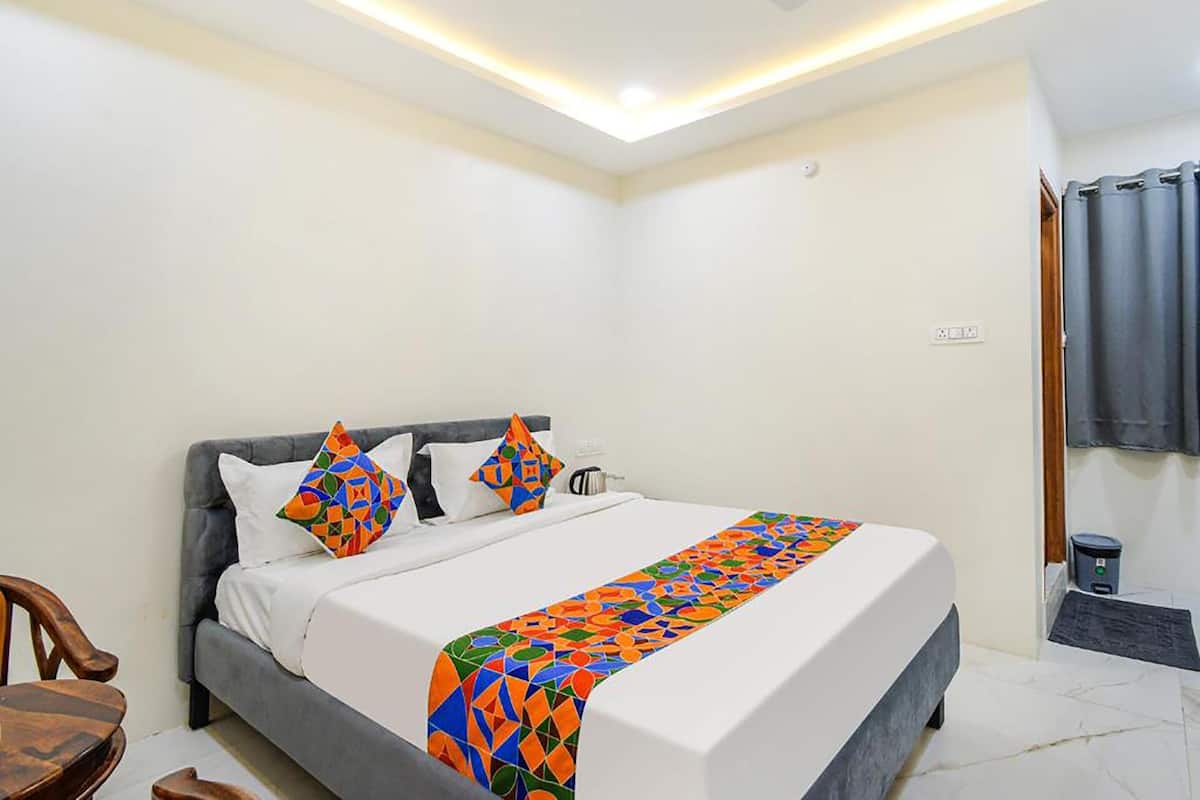 Een moderne hotelkamer met een groot bed, een grijs gestoffeerd hoofdeinde en een kleurrijk bedspread met een geometrisch patroon.