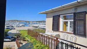 Een balkon met uitzicht op een jachthaven, buitenmeubilair en een gebouw met luiken.