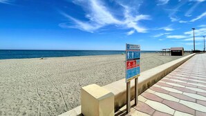 A beach with a signboard, a pathway, and a building labeled 'MASAJE'.