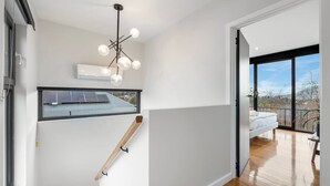 A modern interior with a staircase, a ceiling light fixture, and a view through a window to the outdoors.