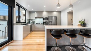 A modern kitchen with a central island, stainless steel appliances, and a bar area with stools.
