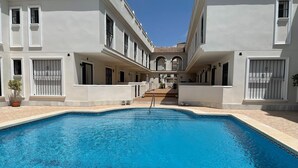A swimming pool surrounded by white buildings with balconies and windows.
