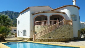 Un bâtiment blanc avec une façade en pierre, une piscine et un escalier menant à un étage supérieur.