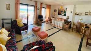 A living room with a sofa, ottomans, a TV, and a dining area with a table and chairs. - Holiday home near the beach on the Costa Tropical (Calahonda)