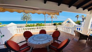A covered outdoor seating area with a table and chairs, overlooking a beach. - Holiday home near the beach on the Costa Tropical (Calahonda)