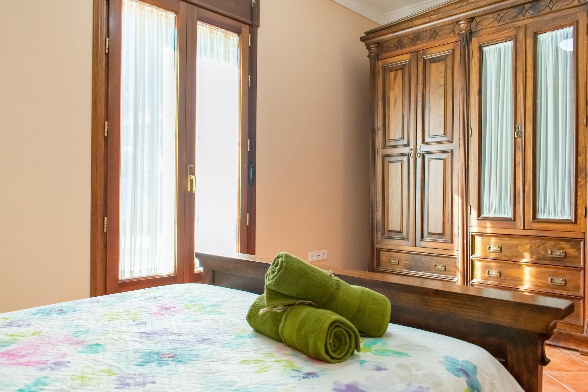 Une chambre d’hôtel avec un lit, une armoire en bois et une fenêtre avec des rideaux.