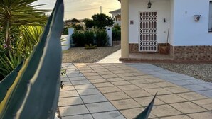 Un edificio residencial con acceso empedrado, puerta con reja y un pequeño porche.