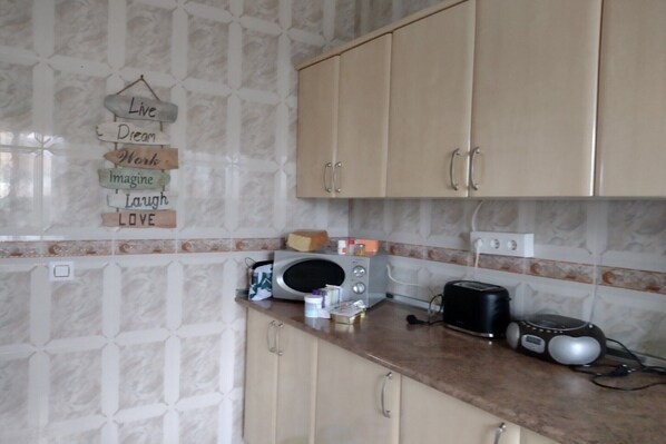 A kitchen with beige cabinets, a microwave, toaster, and a coffee maker on the counter.