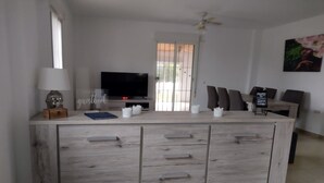 Una sala moderna con televisor, una mesa de centro y un comedor con sillas.