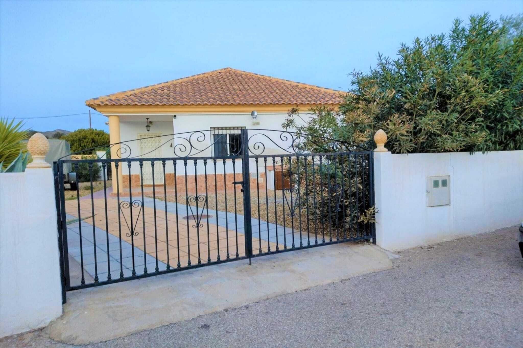 A gated property with a tiled roof, a white exterior, and a paved driveway.