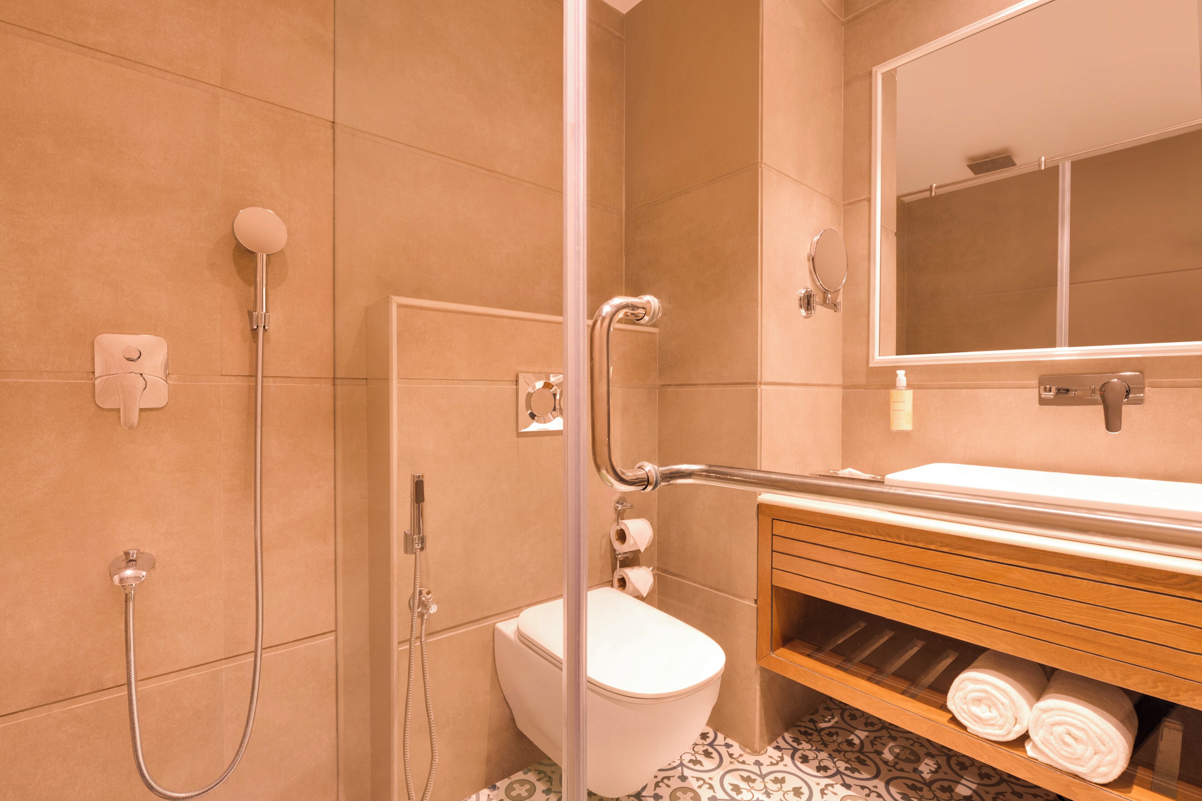 A bathroom with a shower, toilet, and a vanity with towels.