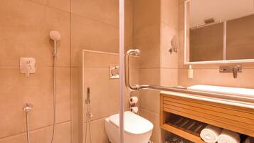 A bathroom with a shower, toilet, and a vanity with towels.