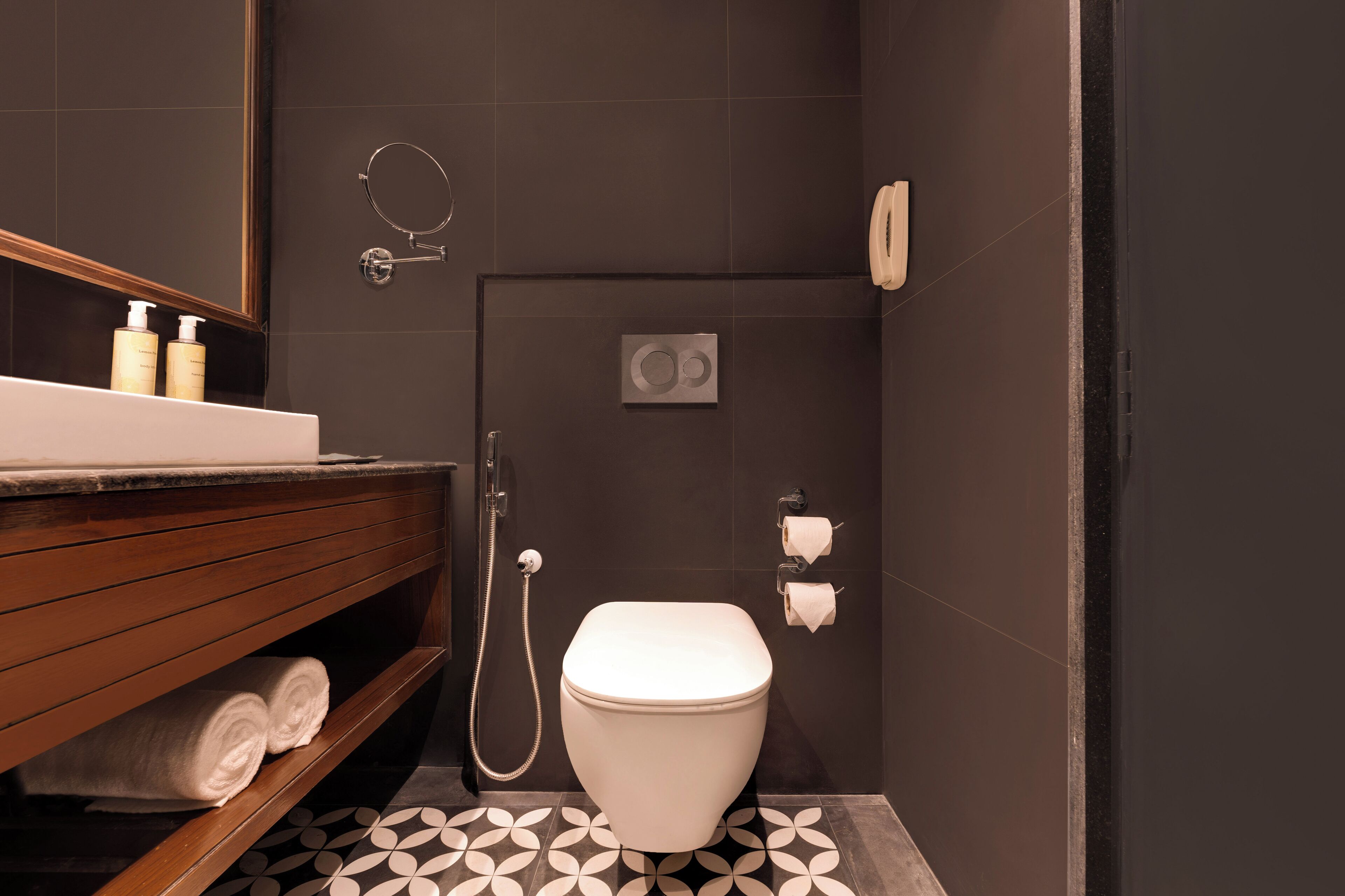 Une salle de bain moderne avec des toilettes blanches, un meuble-lavabo en bois, un miroir et une douche.