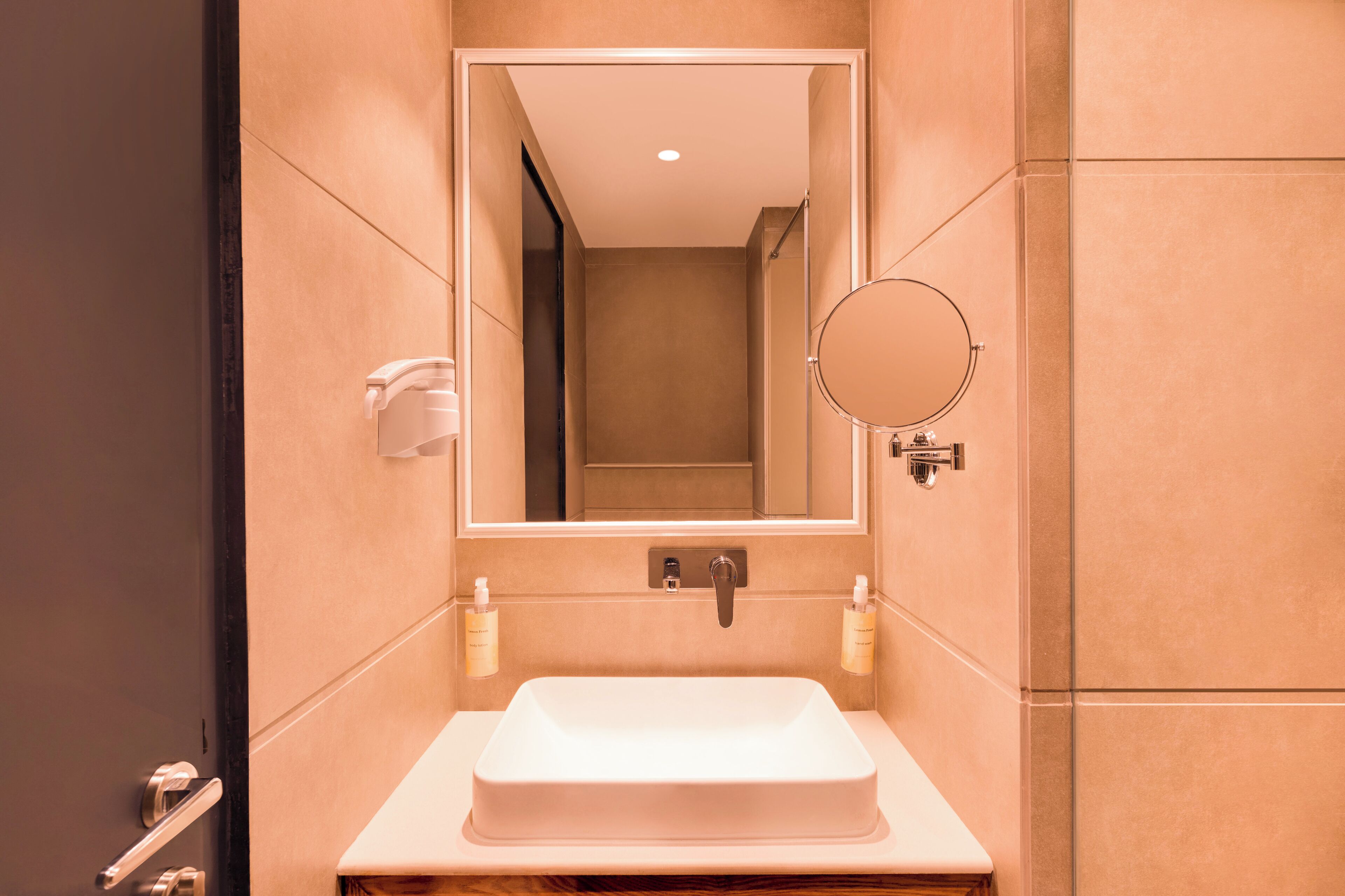 Un baño moderno con un lavamanos rectangular, un espejo y dos dispensadores de jabón para manos.