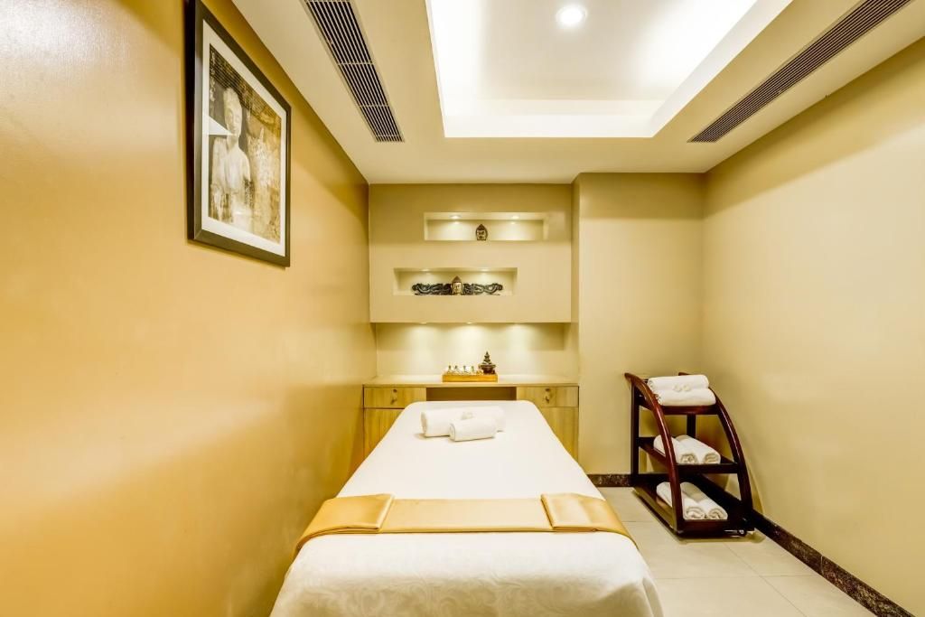 A hotel room with a bed, a shelf with decorative items, and a towel rack.