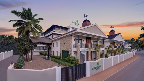A modern hotel with a stone facade, multiple balconies, and a gated entrance.