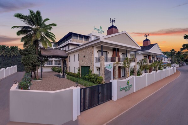 A modern hotel with a stone facade, multiple balconies, and a gated entrance.