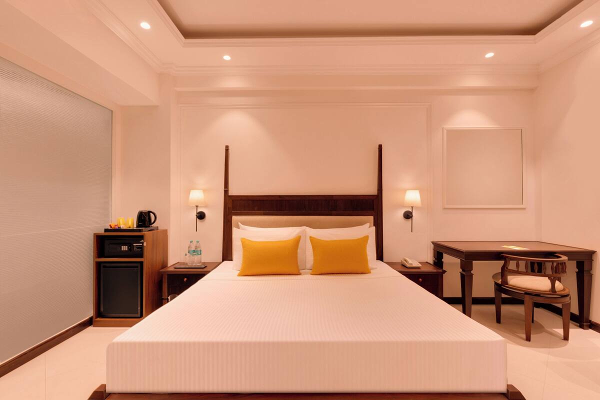 Una habitación de hotel con una cama grande, mesitas de noche, un escritorio y una silla.