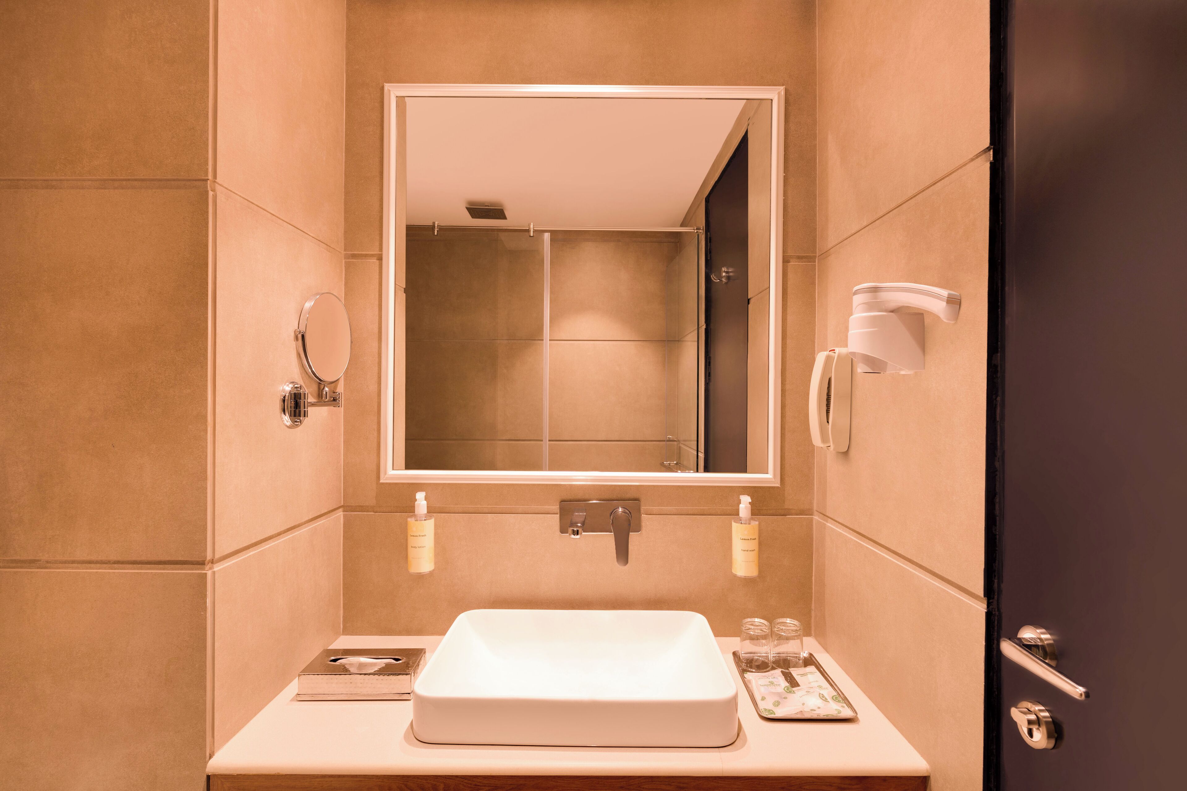 Un baño moderno con un espejo grande, un lavabo y dos secamanos.